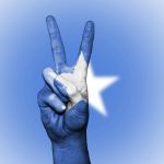 A hand making a peace gesture painted with the Somali flag colors, symbolizing national unity.